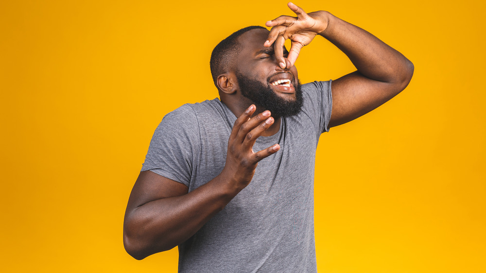 Man holding his nose after smelling something bad