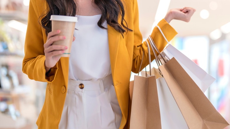 Woman holding coffee and shopping bags