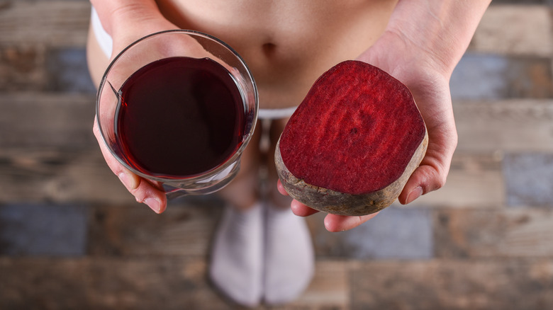 woman holding half a beet and glass of beet juice