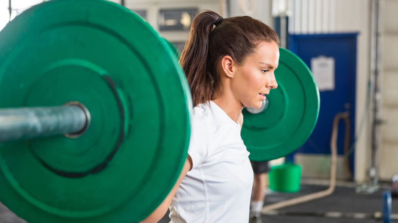 woman lifting barbell at the gym
