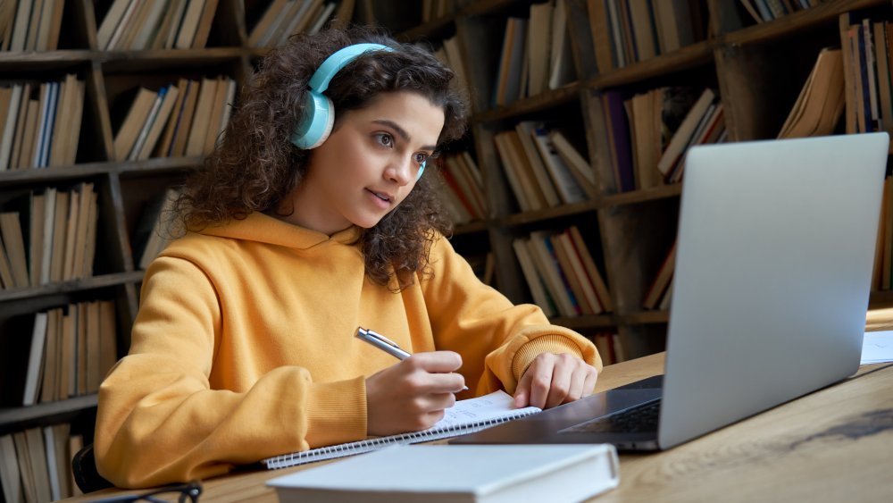 Teen girl with dark curly hair on zoom call with headphones on