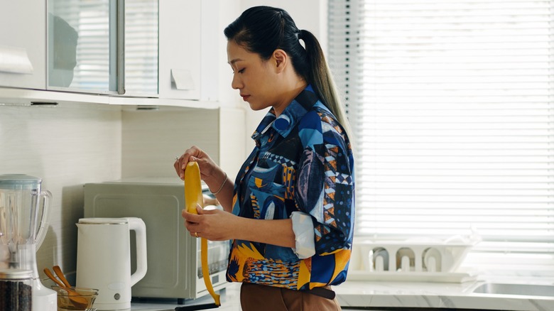 Woman peeling banana in the kitchen