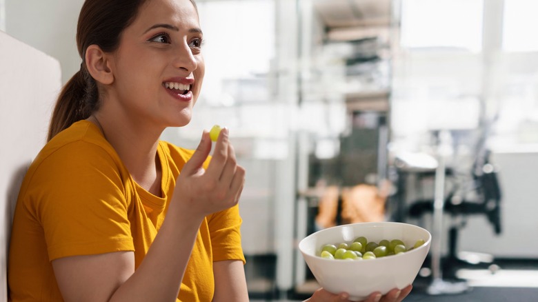 Woman eating a bowl of grapes