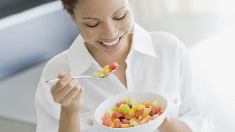 Smiling woman eating a bowl of fruit