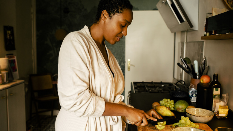 Woman cutting kiwi in her kitchen