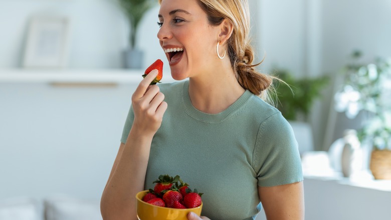 Woman eating strawberries in her kitchen