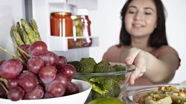 Woman putting broccoli in the refrigerator