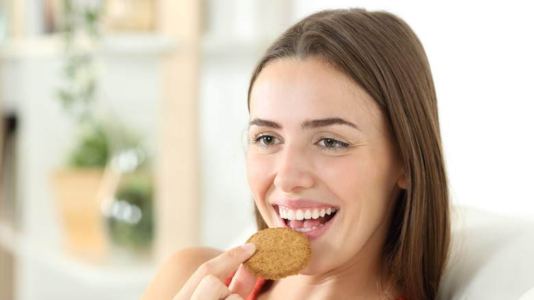 Young woman eating crackers at home