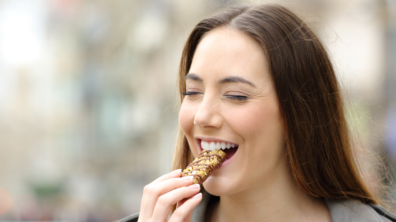 Woman outside eating a snack bar