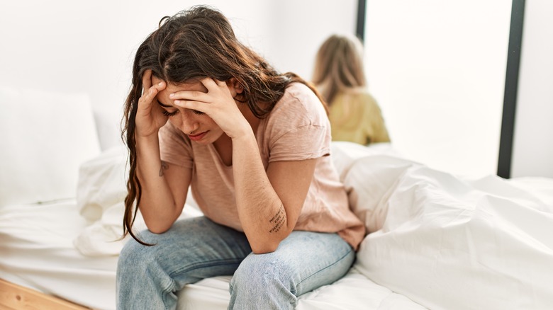 Upset couple sitting on opposite sides of bed