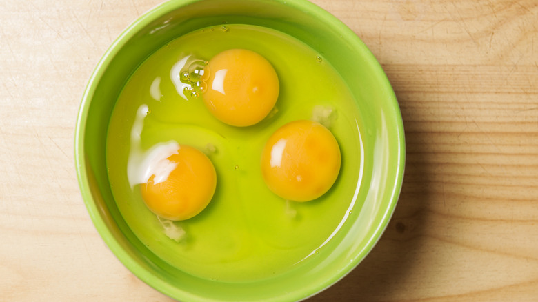 Three raw eggs in a green cup