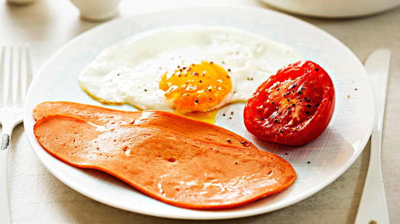 meat-free bacon slices on plate with egg and tomato