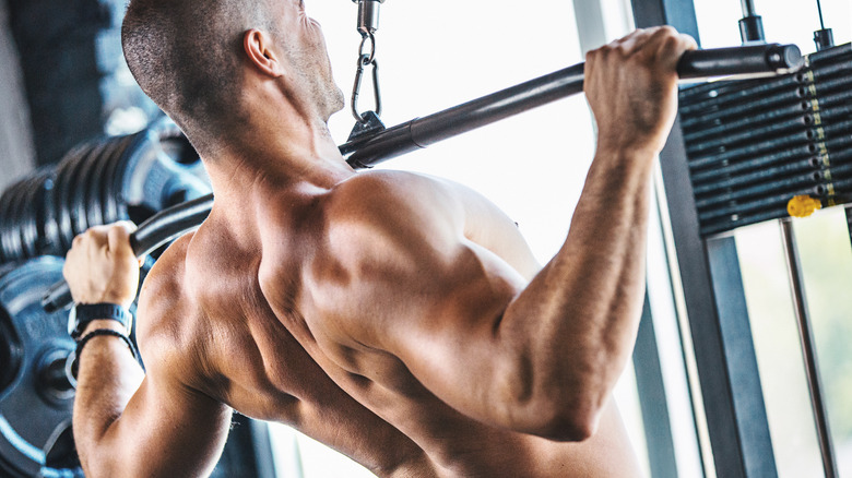 shirtless muscular man doing lat pulldown