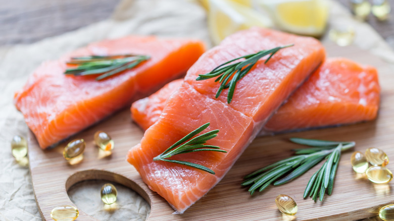 Salmon on a cutting board along with omega-3 supplements