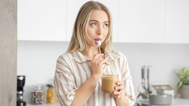 woman eating sunflower butter from the jar