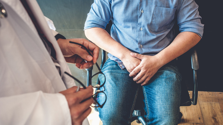 man holding his genital area while seeing a doctor