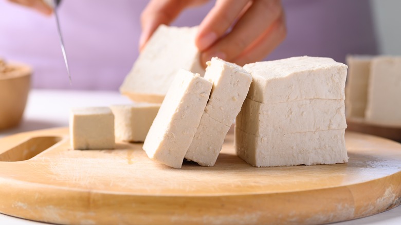 Woman slicing firm tofu blocks