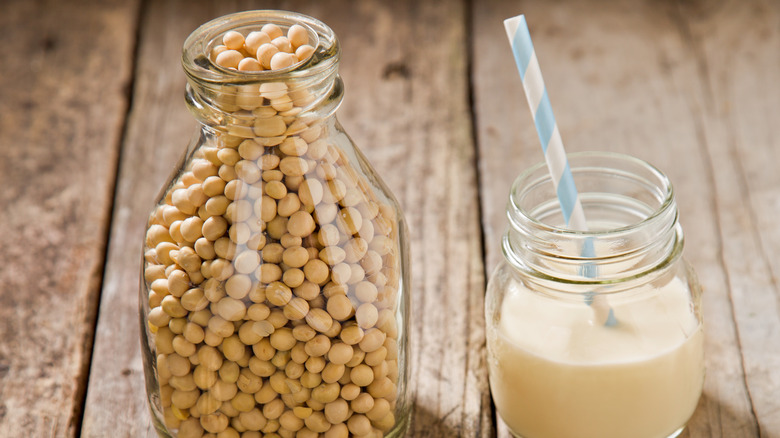 Glass of soy milk next to jar of soy beans