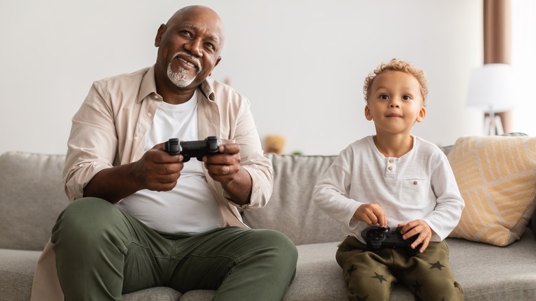 Older man playing video games with young child