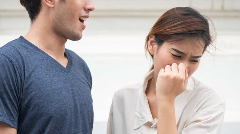 woman holding nose near man