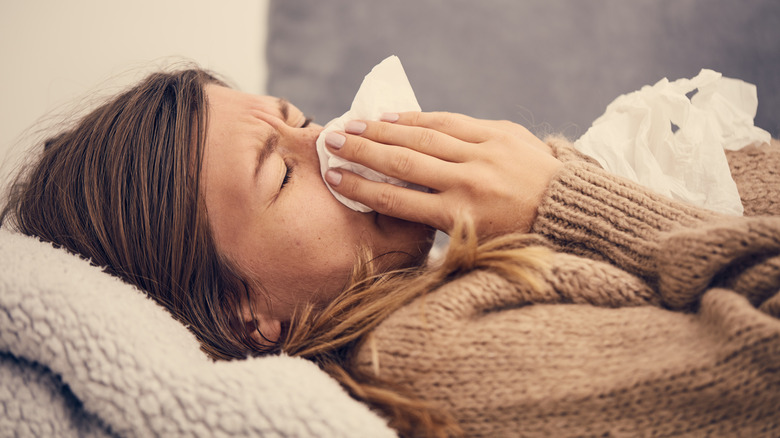 woman in bed sneezing