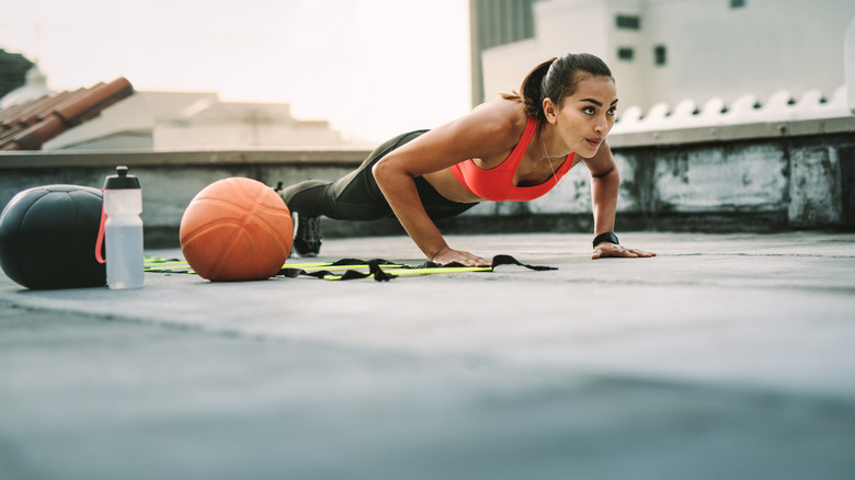Woman doing push-up with basketball