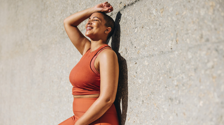 Woman in workout gear leaning against wall