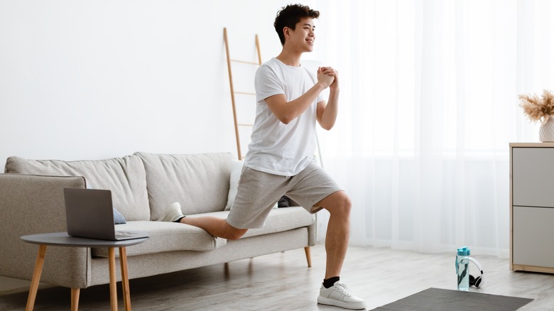 Man doing split squats on sofa