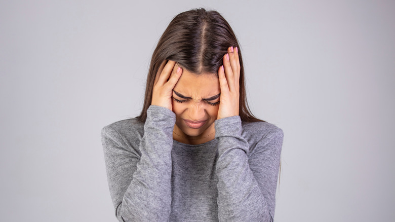 Woman holding the sides of her head 