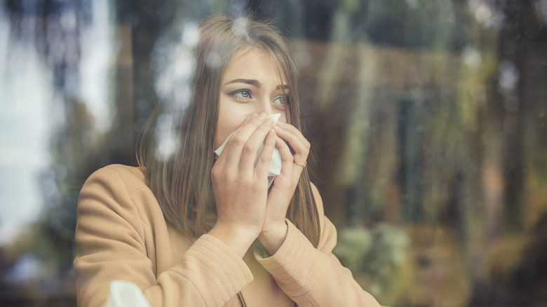 woman with allergies looking out window