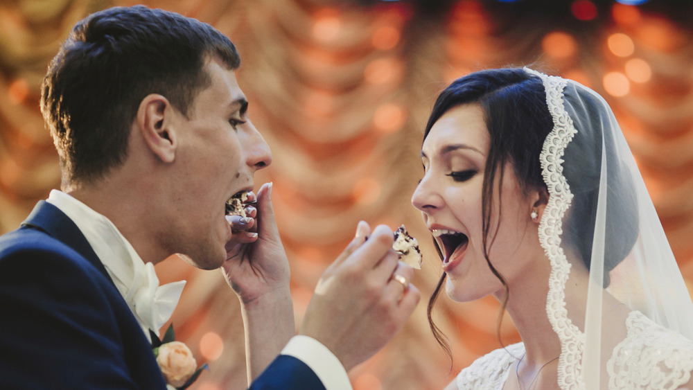 man and woman exchanging cake at wedding