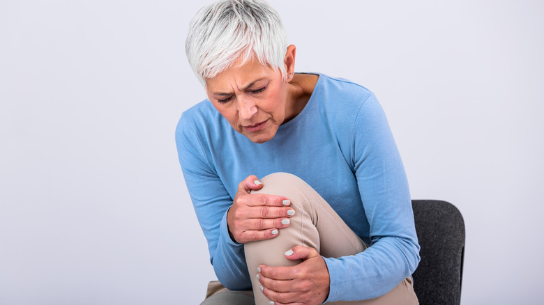 Woman in 50s grasping knee in pain