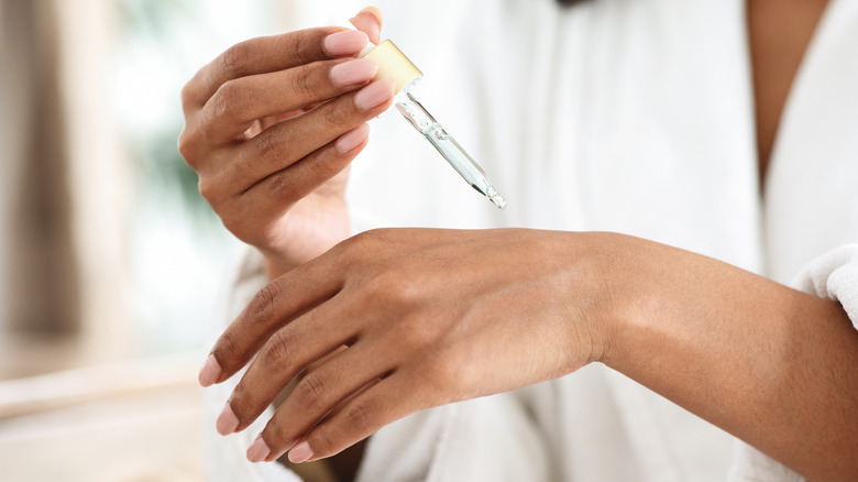 person applying an oil to their finger via dropper