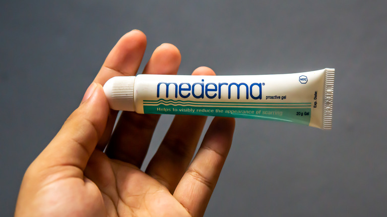 person holding a tube of mederma in their hand