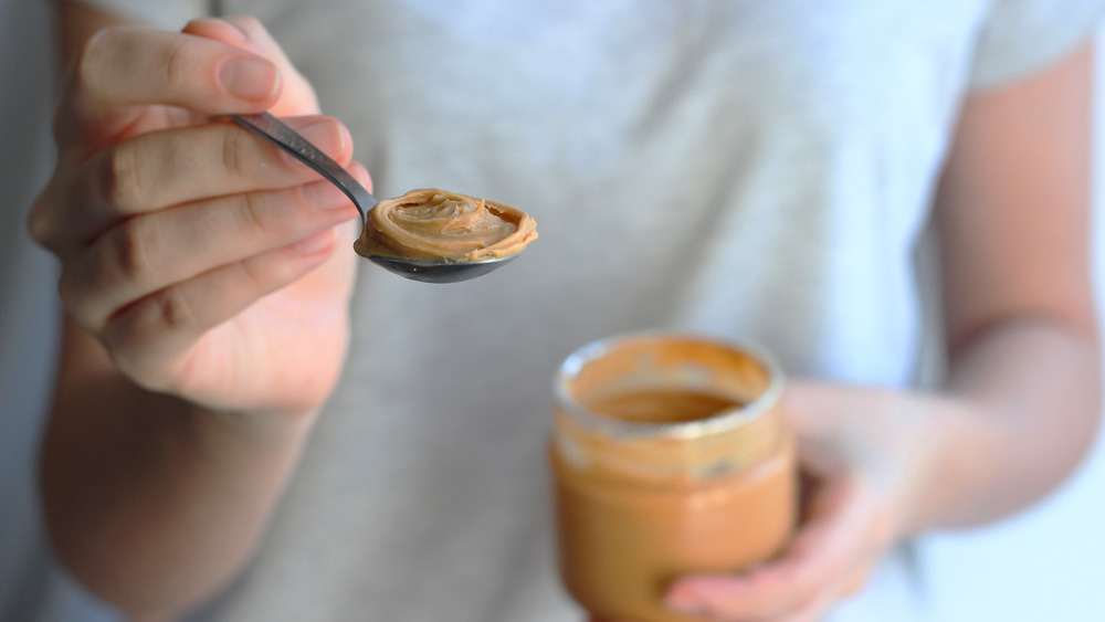 woman holding spoonful of peanut butter