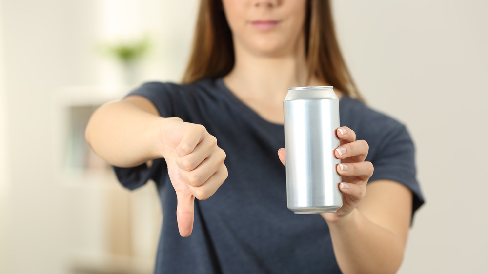 woman avoiding can of soda