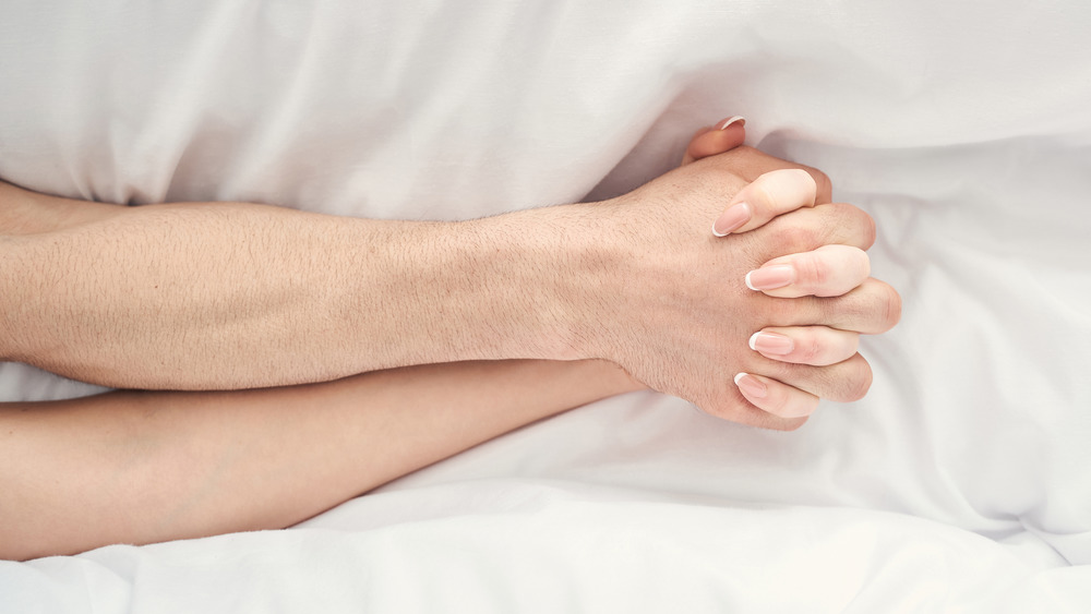 couple holding hands in bed