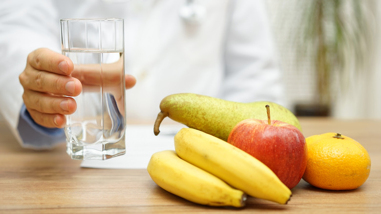 doctor with glass of water next to fruit