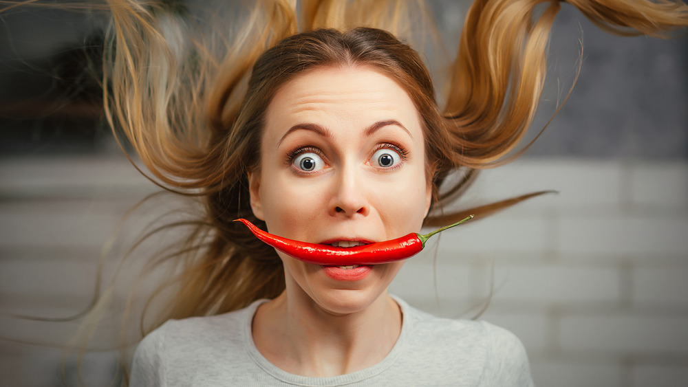 woman with spicy pepper in mouth