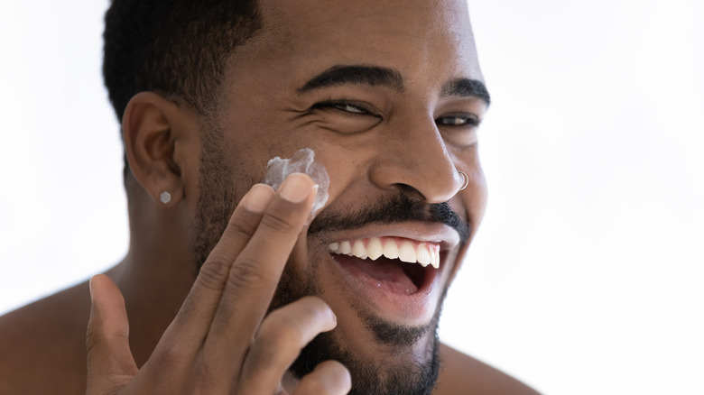 a black man applying cream to his face happy skincare