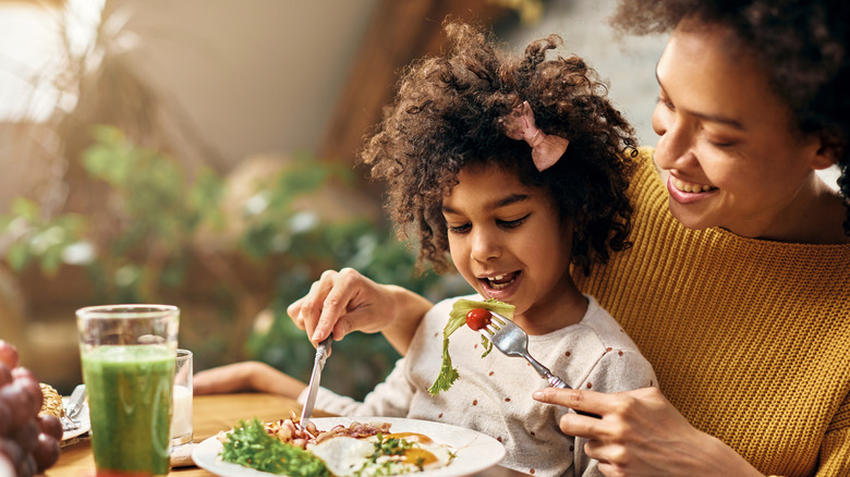 mother with daughter eating healthy breakfast 