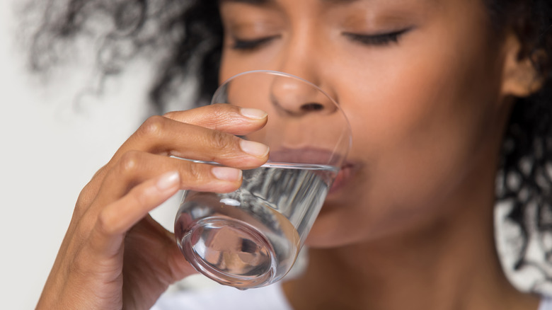 black woman drinking a glass of water in the morning