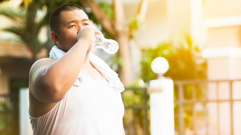 overweight man overheating, drinking water