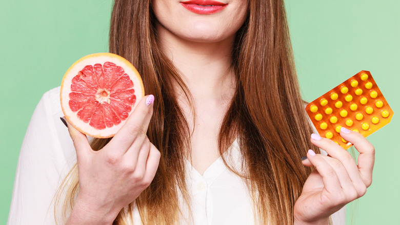 Woman holding grapefruit and pills