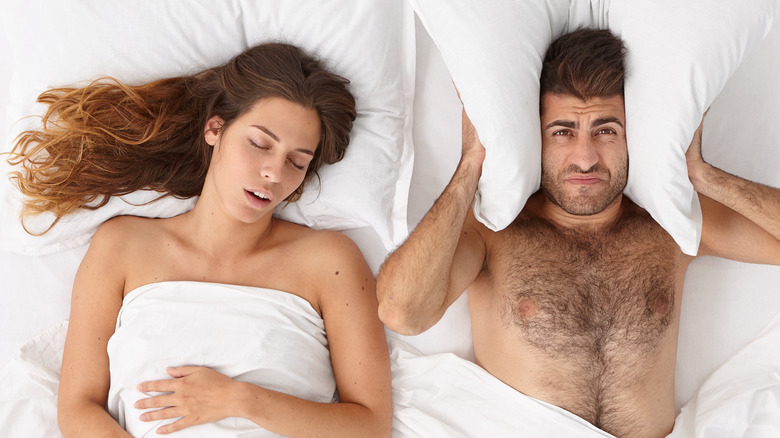 man covering ears with woman sleeping