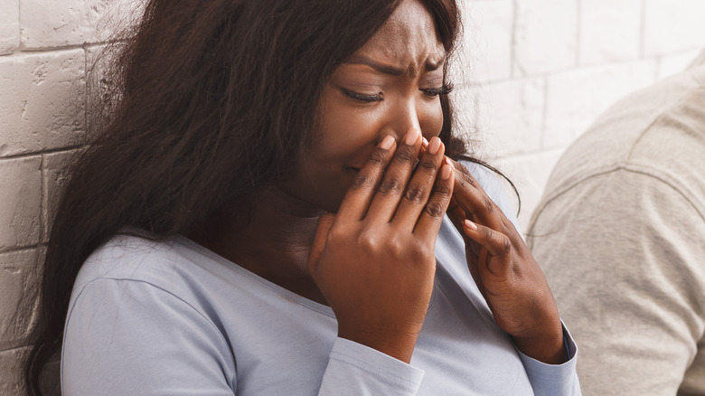 disgusted pregnant woman covering nose 