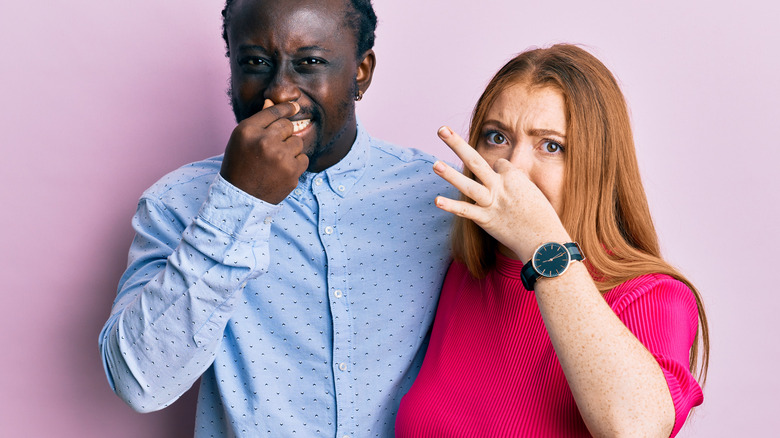 interracial pregnant couple holding noses