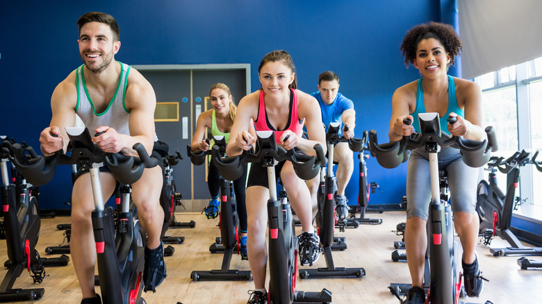 Five people smiling while exercising together during a spin class