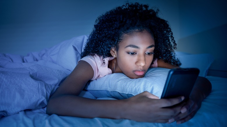 girl staring at phone in bed