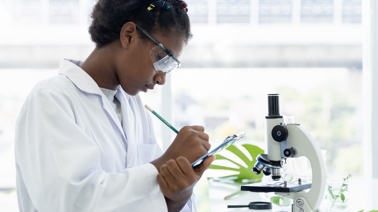 Researcher looking at bacteria and writing